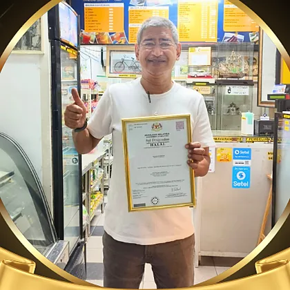Encik Syed Azaman of Kafe Jong Berlaboh holding a framed halal certificate